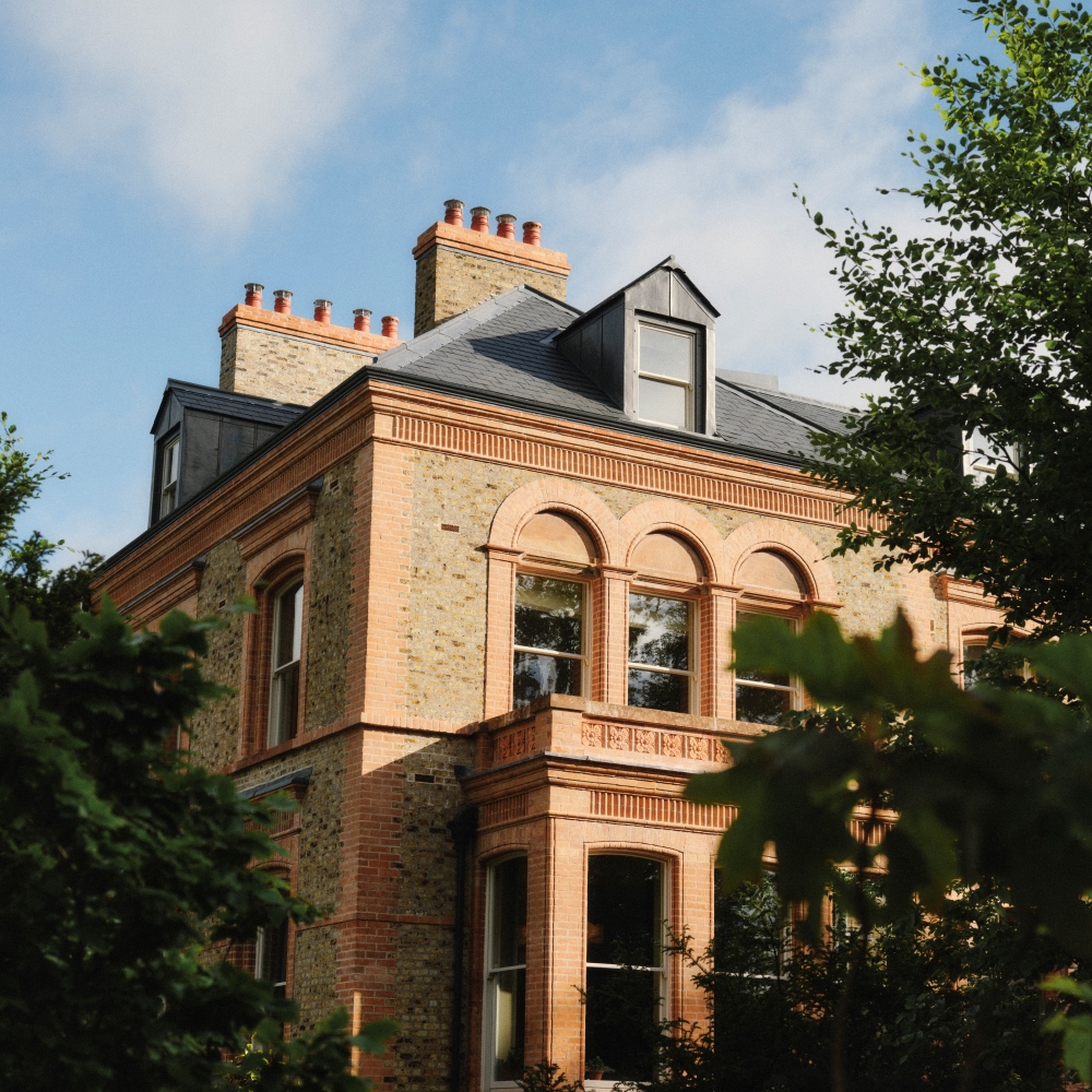 Ómós Guesthouse in Abbeyleix, County Laois, with its restored Victorian red-brick exterior surrounded by mature trees.