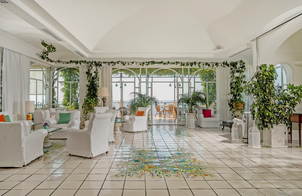 Light-filled lounge at Santa Caterina Hotel in Amalfi, with white arches, tiled floors and garden views