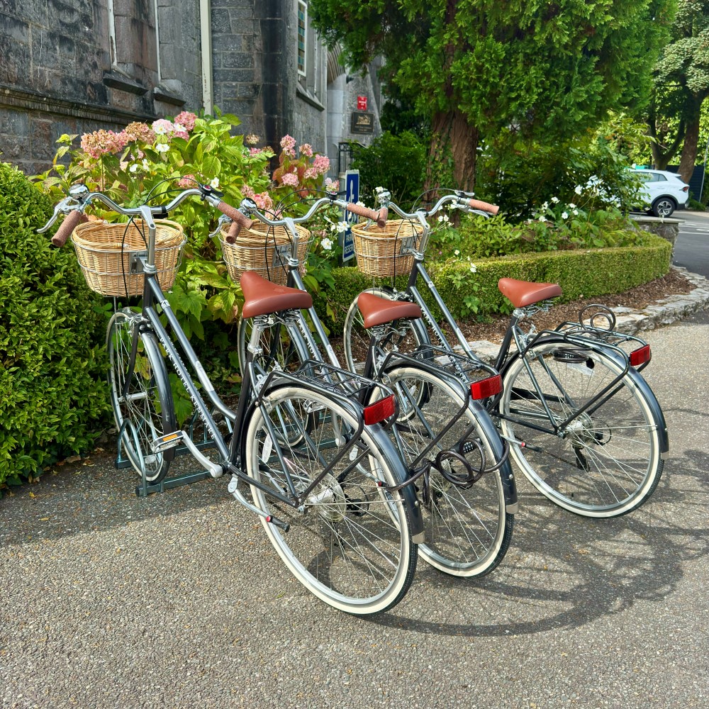 Complimentary bicycles for guests at Park Hotel Kenmare surrounded by flowers and greenery in County Kerry, Ireland