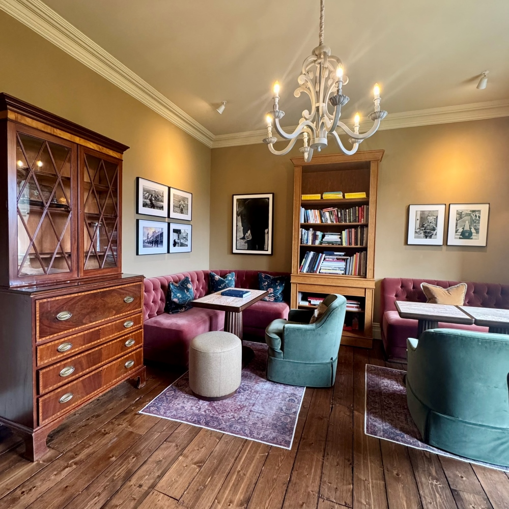 Elegant library at Park Hotel Kenmare with bookshelves, artwork, a chandelier and comfortable seating in County Kerry, Ireland